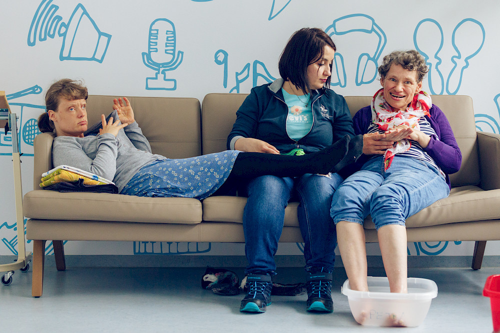 Bild zeigt mehrere Personen auf einem Sofa.