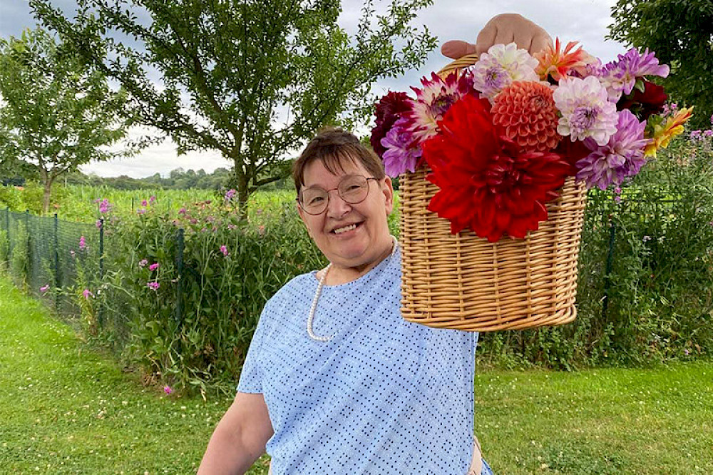 Bild zeigt eine Frau mit einem großen Blumenkorb.