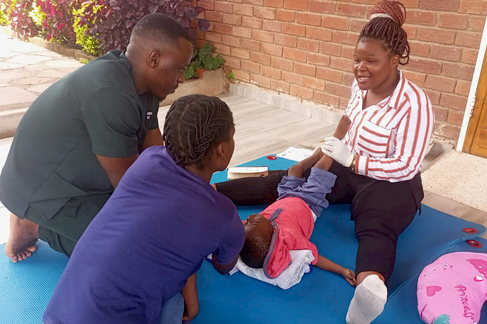 Bild zeigt Personen bei Therapieübungen mit einem Kind.
