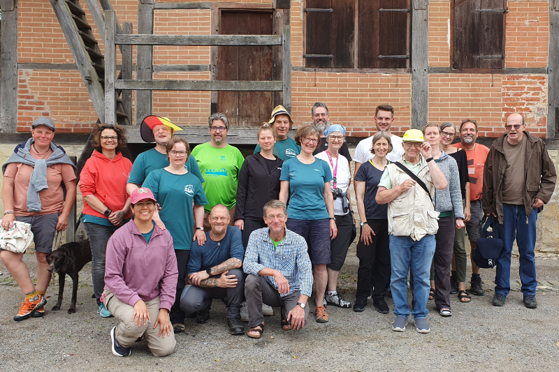 Das Bild zeigt eine Gruppe von Menschen vor einem alten Fachwerkhaus